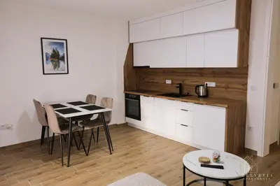 a kitchen with white cabinets and a table with chairs at Helvetia Apartments in Jajce