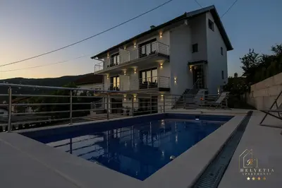 a villa with a swimming pool in front of a house at Helvetia Apartments in Jajce
