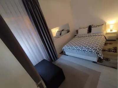 a white bedroom with a bed and a window at Apartman San in Bihać