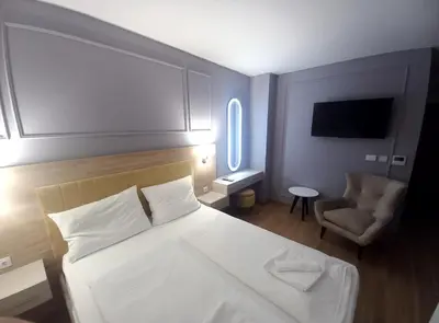a bedroom with a white bed and a chair at MN apartman in Banja Luka