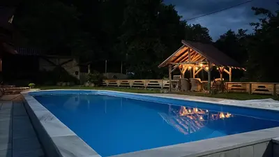 a swimming pool in front of a cabin at night at Dragon's Lodge in Visoko