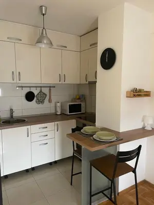 a kitchen with white cabinets and a wooden table at Evergrey in Banja Luka