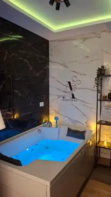 a bath tub in a room with a stone wall at Apartman Atrium Banja Luka in Banja Luka