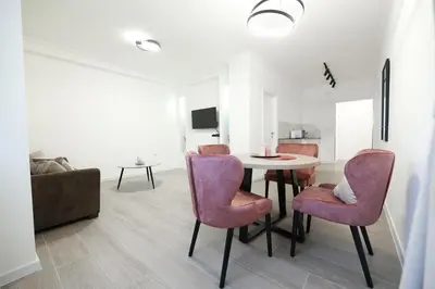 a living room with a table and pink chairs at Central Point Apartmani, Banja Luka in Banja Luka