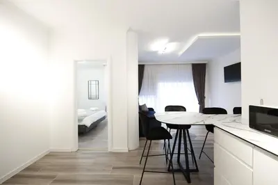 a kitchen with a table and chairs and a bedroom at Central Point Apartmani, Banja Luka in Banja Luka