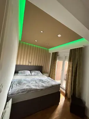 a bedroom with a bed with a green lighting at Apartmani Kastel 3 in Banja Luka