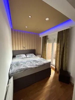 a bedroom with a large bed with a blue lighting at Apartmani Kastel 3 in Banja Luka
