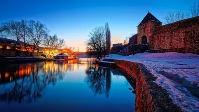 a river with snow on the ground next to a building at Apartmani Kastel 3 in Banja Luka