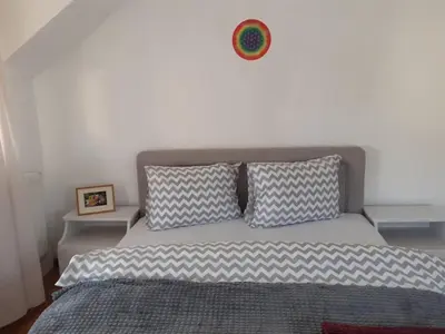 a bed with two pillows and a clock on the wall at Komforni Apartmani Banja Luka in Banja Luka