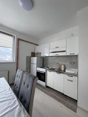 a kitchen with white cabinets and a table and chairs at Stan na dan GlobusMG in Mrkonjić Grad