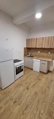 a kitchen with white appliances and a wooden floor at Stan Banja Luka Paprikovac in Banja Luka