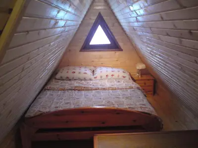 a bed in a wooden room with a window at Endzi VS Vlašić in Travnik