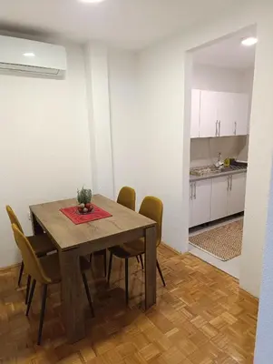 a dining room with a table and chairs and a kitchen at Apartman Bulevar Živinice in Živinice