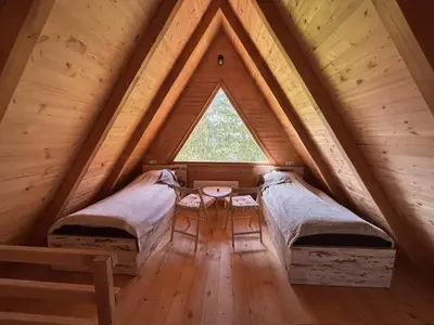 a attic room with two beds and a window at Planinska kuća Rea, Vlašić in Vlasic