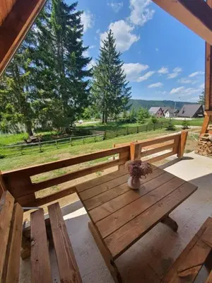 a wooden bench on a patio with a view of a field at Planinska kuća Rea, Vlašić in Vlasic