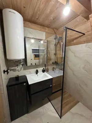 a bathroom with a sink and a shower with a mirror at Planinska kuća Rea, Vlašić in Vlasic