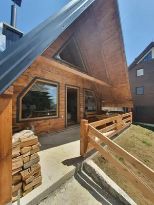 a wooden cabin with a fence and a building at Planinska kuća Rea, Vlašić in Vlasic