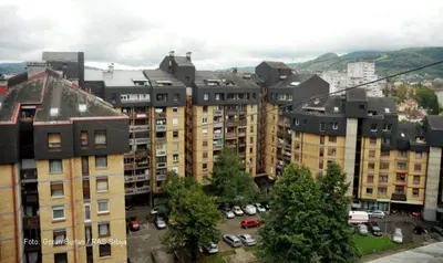 a group of buildings with cars parked in a parking lot at Apartment 27 small in Banja Luka