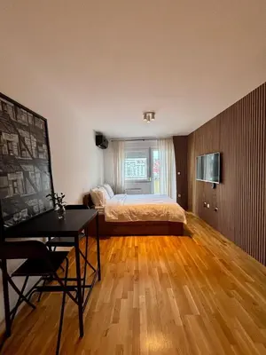a bedroom with a bed and a desk and a window at Apartman MINI in Doboj