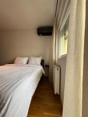 a bedroom with a white bed and a window at Apartman MINI in Doboj