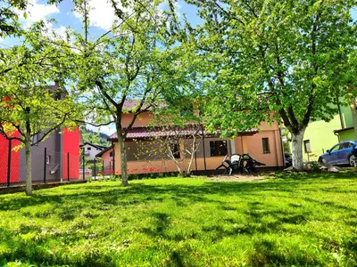 a green yard with trees in front of a building at Apartment Residence House in Bihać