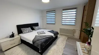 a bedroom with a large bed and two windows at HomeSpot Banja Luka in Banja Luka