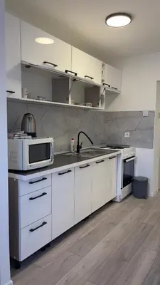 a kitchen with white cabinets and a microwave at HomeSpot Banja Luka in Banja Luka