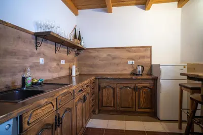 a kitchen with wooden cabinets and a sink and a refrigerator at Planinska Kuća OBLAK in Kupres