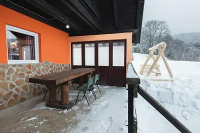 a house with a wooden table and chairs in the snow at Planinska Kuća OBLAK in Kupres