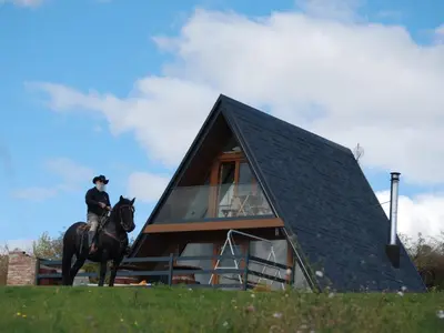 a person riding a horse in front of a house at Mountain house Tomislavgrad in Tomislavgrad