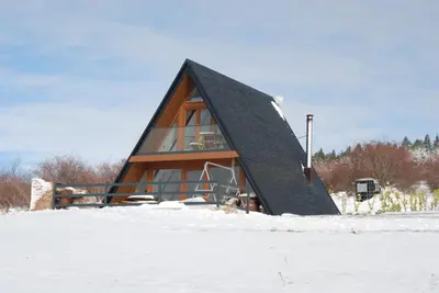 a house with a black roof in the snow at Mountain house Tomislavgrad in Tomislavgrad