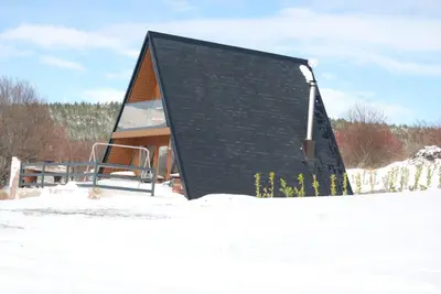 a small house with a black roof in the snow at Mountain house Tomislavgrad in Tomislavgrad