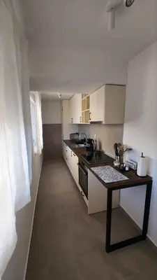 a kitchen with white cabinets and a black counter top at Apartman Milica in Banja Luka