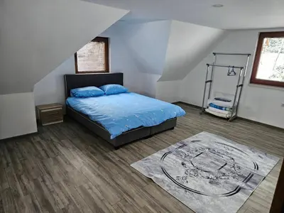 a bedroom with a bed with blue sheets and a rug at Vikendica Bilanović in Donji Vakuf