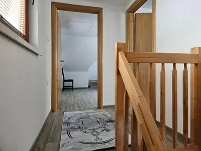 a hallway with a wooden staircase and a door with a rug at Vikendica Bilanović in Donji Vakuf