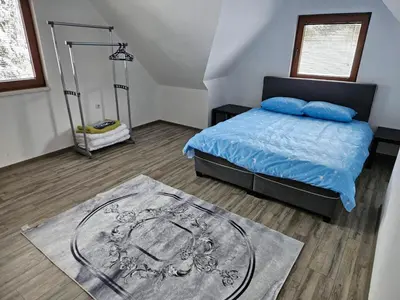 a bedroom with a bed with blue pillows and a rug at Vikendica Bilanović in Donji Vakuf