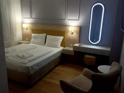a bedroom with a bed with a mirror and a chair at MN apartman in Banja Luka