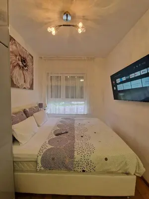 a bedroom with a bed with a tv on the wall at Apartmani Stan na dan 34 in Banja Luka
