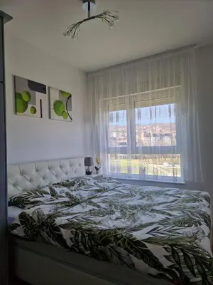 a bedroom with a bed with a large window at Apartmani Stan na dan 34 in Banja Luka