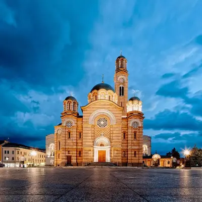 a large building with a clock tower at night at Apartmani Stan na dan 34 in Banja Luka
