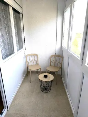 two chairs and a table in a room with two windows at Apartment Sneki Banja Luka in Banja Luka