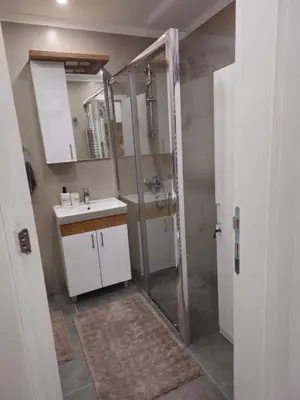 a bathroom with a shower and a sink and a mirror at Apartman Dora in Doboj