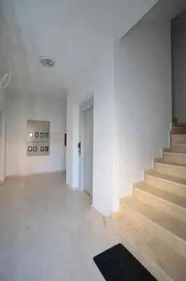a hallway with stairs in a white building at Apartman Dentalux 1 in Banja Luka