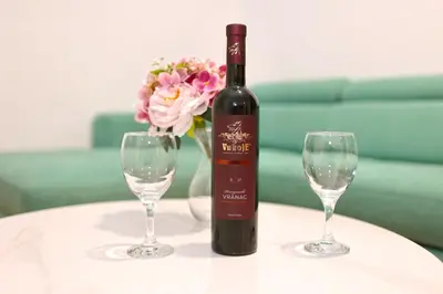 a bottle of wine and two wine glasses on a table at Apartman Dentalux 1 in Banja Luka