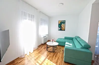 a living room with a green couch and a table at Apartman Dentalux 1 in Banja Luka