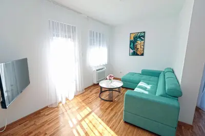 a living room with a green couch and a table at Apartman Dentalux 1 in Banja Luka