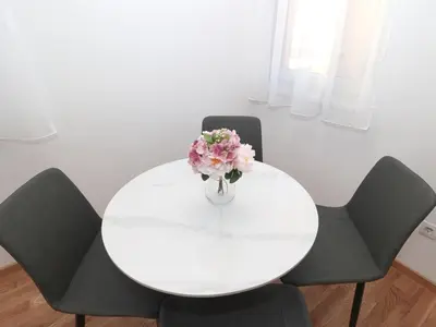 a white table with chairs and a vase of flowers at Apartman Dentalux 2 in Banja Luka
