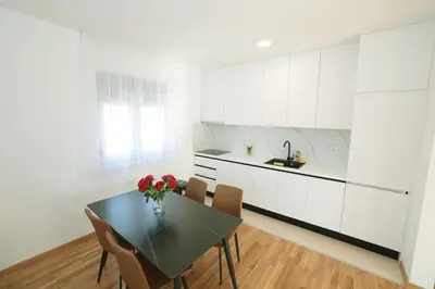 a kitchen with a table and chairs and a kitchen with white cabinets at Apartman Dentalux 3 in Banja Luka