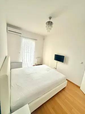a white bedroom with a bed and a window at Apartman Dentalux 5 in Banja Luka