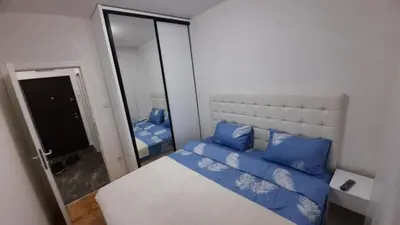 a bedroom with a bed with blue pillows and a mirror at Zlatni San apartman 1 in Banja Luka